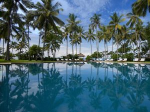 Luxury beachfront infinity pool at a Candidasa resort reflecting palm trees and a clear blue sky
