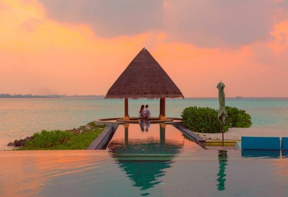Couple enjoying an oceanfront pool sunset on a tailor-made Indonesia trip