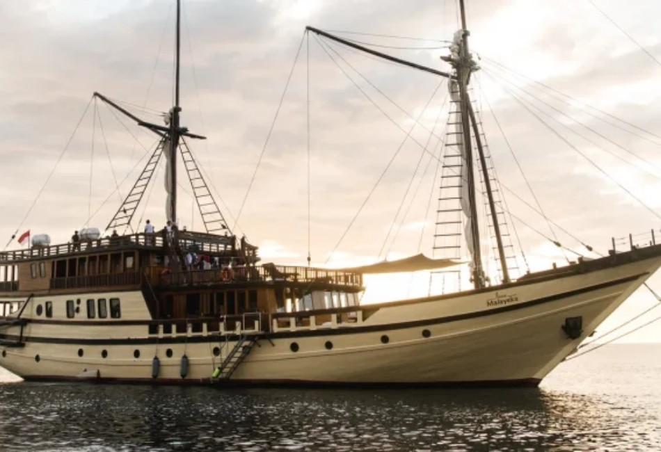 Traditional private phinisi boat sailing at sunset in Indonesia