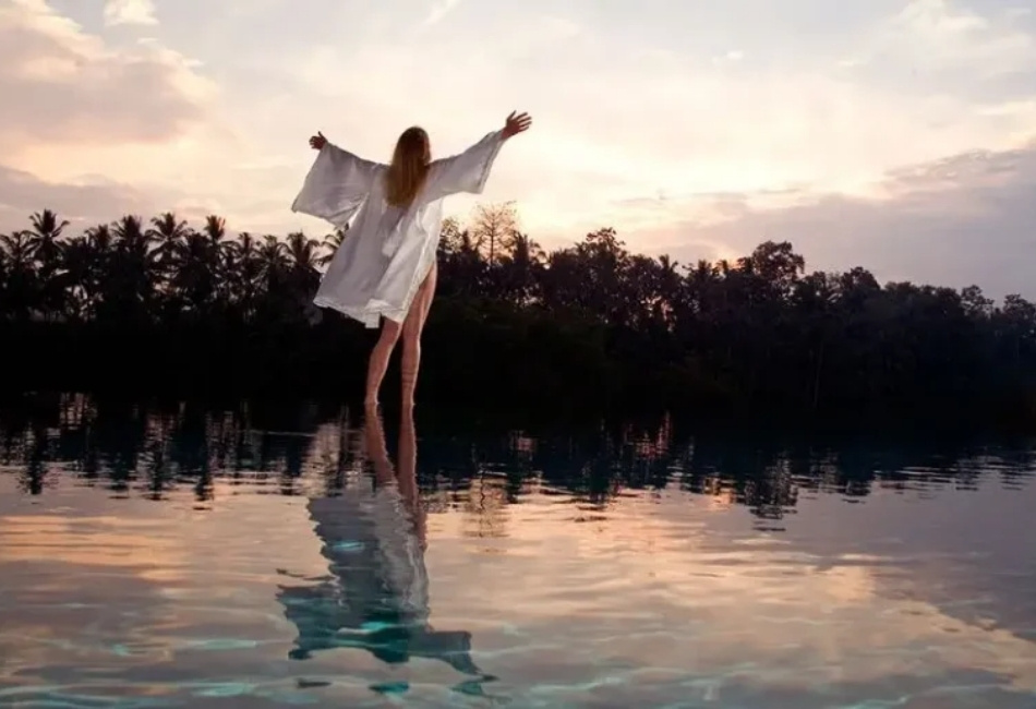 Woman enjoying an infinity pool sunset on a luxury wellness tour in Indonesia