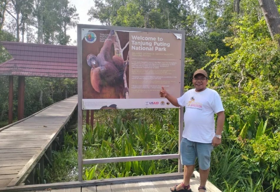 Visitor beside Tanjung Puting National Park information sign in Kalimantan