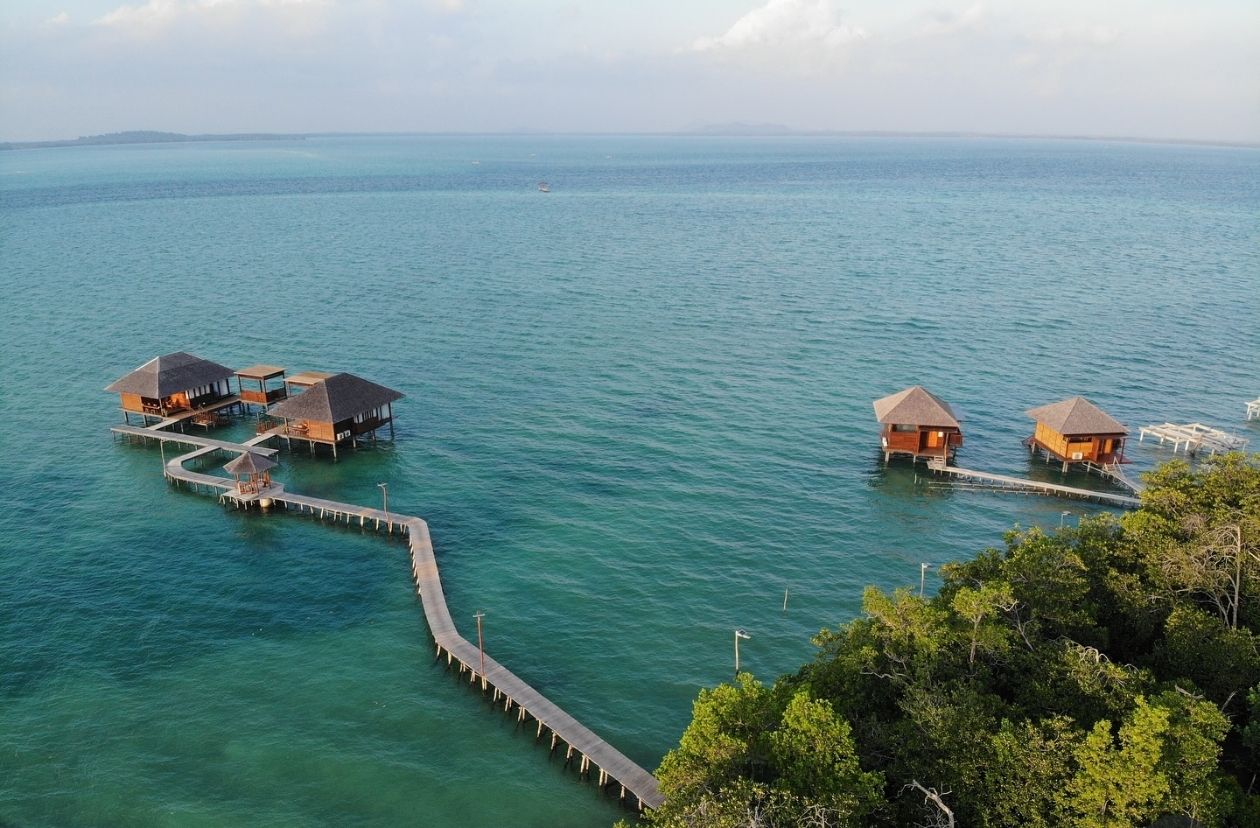 ="Wooden pier and seaside gazebos at Leebong Island, Belitung — tranquil private resort surrounded by turquoise waters and tropical mangroves