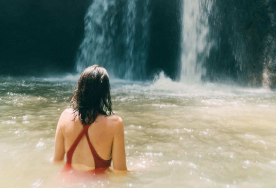 Woman swimming in waterfall in Bali